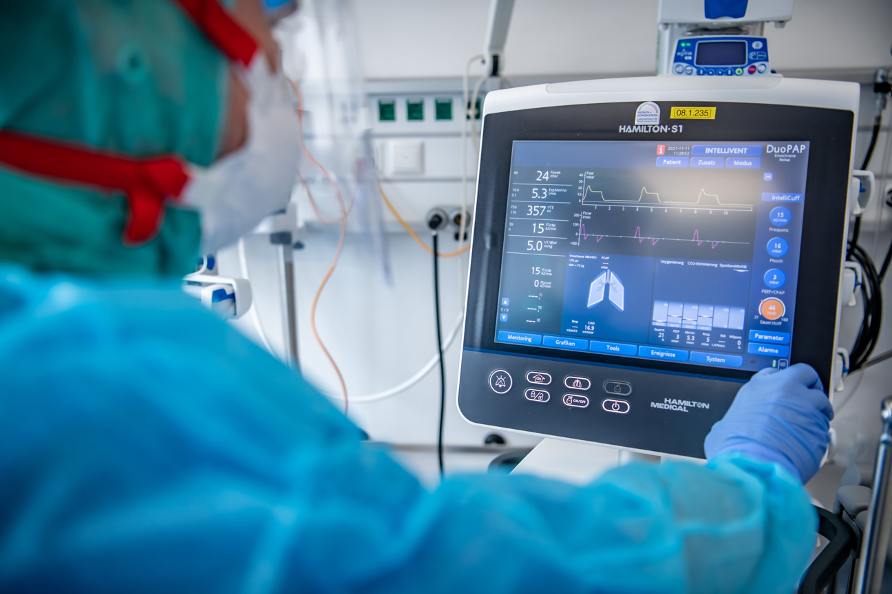 Person in Schutzkleidung bedient ein medizinisches Gerät