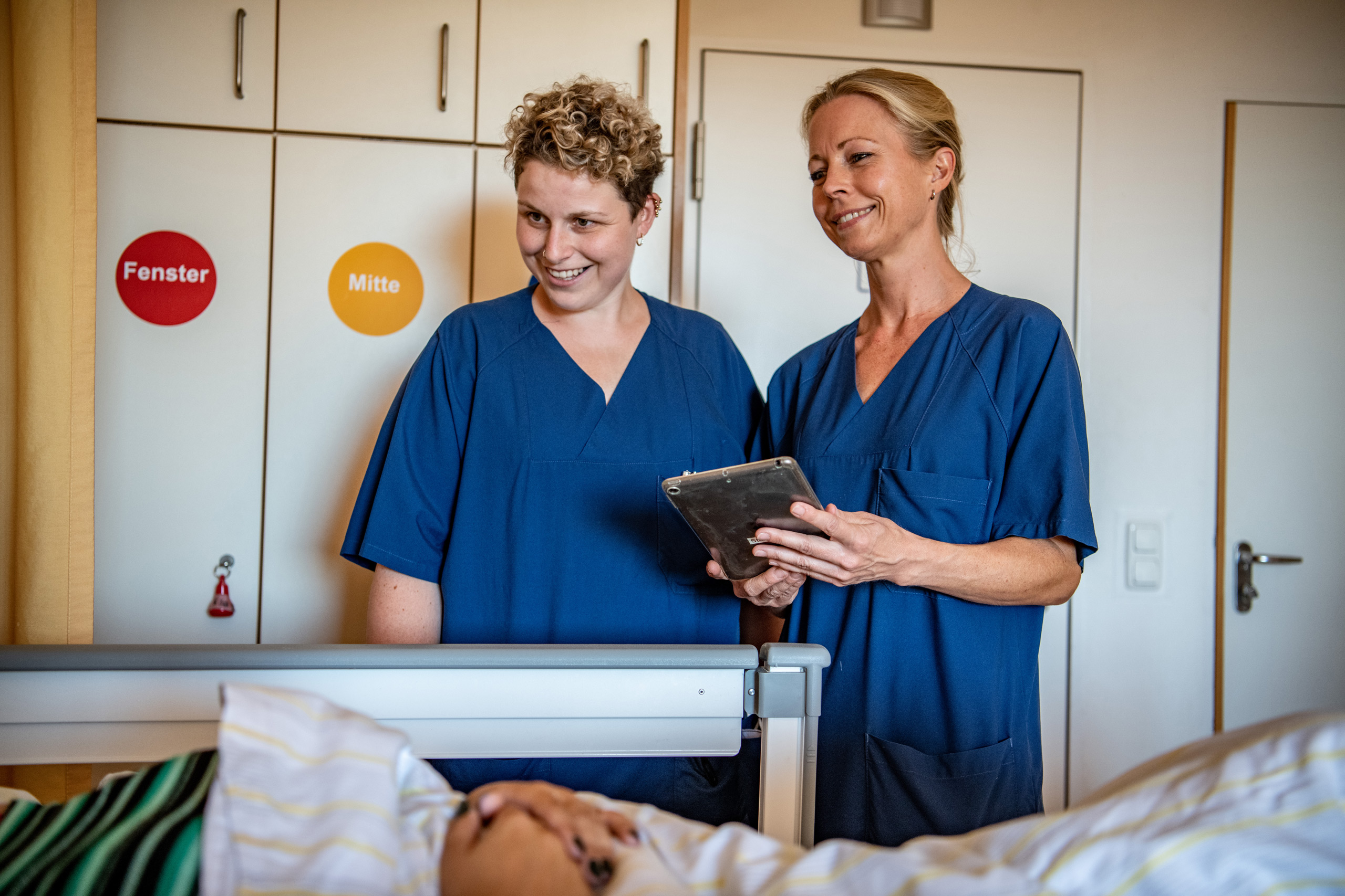Zwei Krankenpflegerinnen in einem Patientenzimmer
