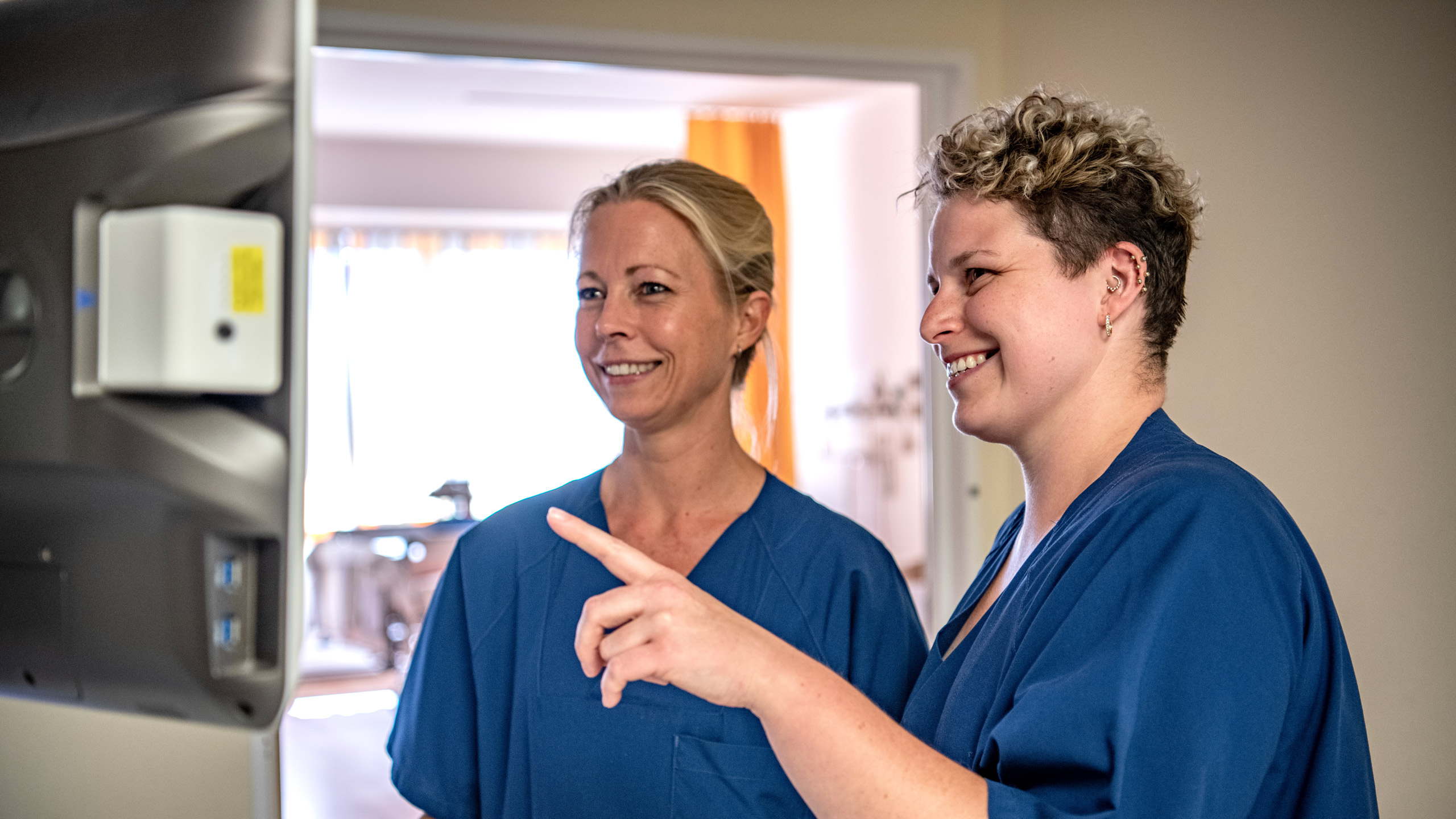 zwei Krankenpflegerinnen sehen sich etwas auf einem Bildschirm an
